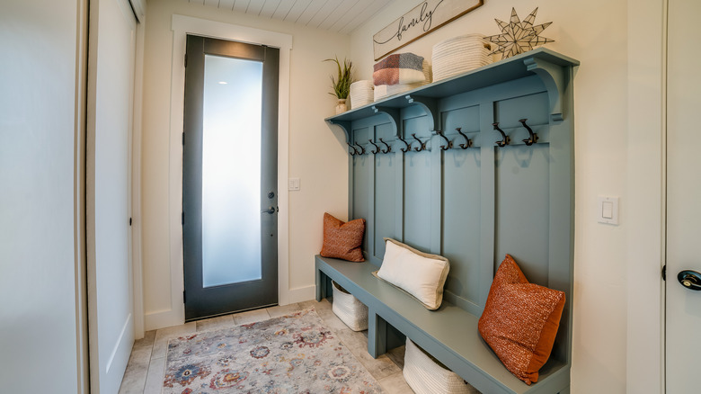 Home entryway featuring a built-in bench and coat hangers with throw pillows and an area rug