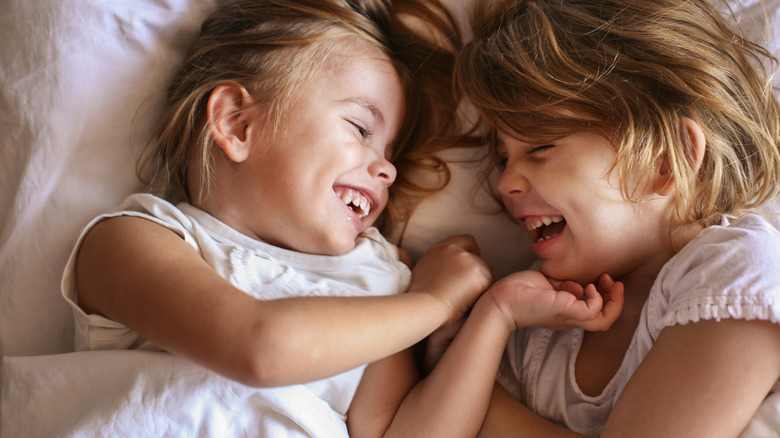 Two girls lying in bed giggling
