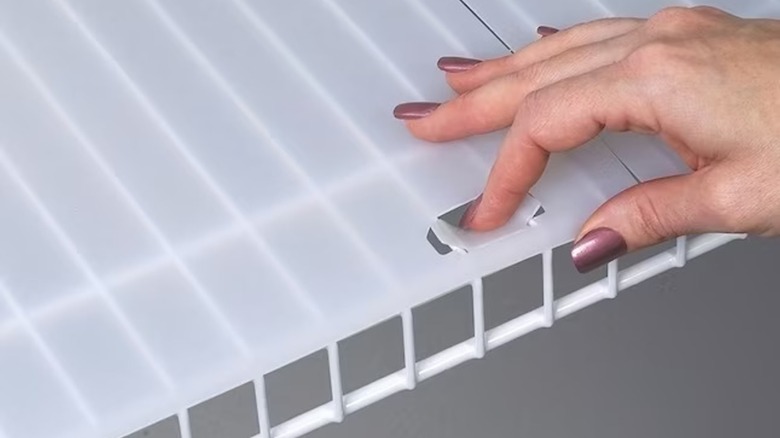 A person lifting a shelf liner