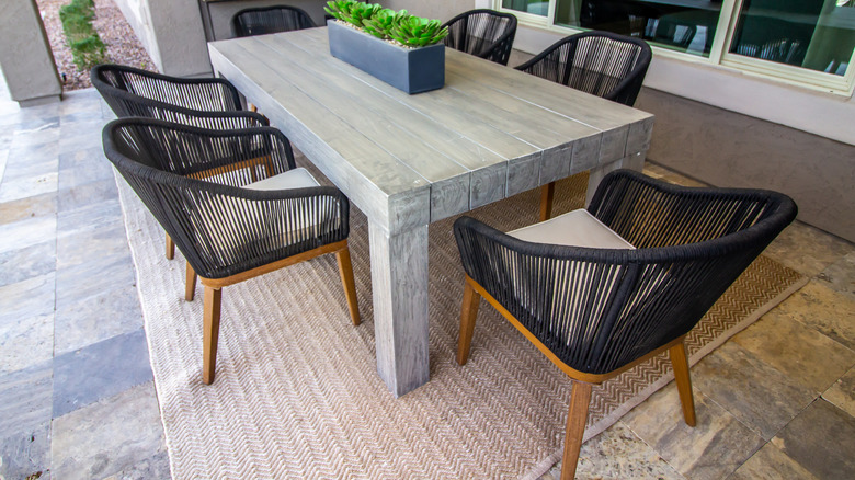 A patio with outdoor dining furniture on an area rug