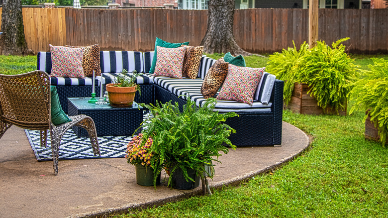 A backyard patio with a couch and patterned throw pillows