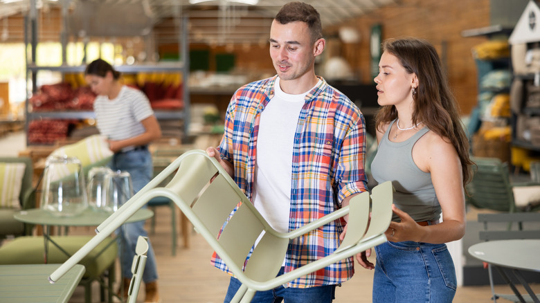 Two people holding a patio chair in a furniture store