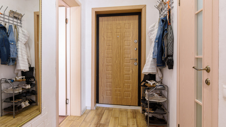 Front door leading to a small entryway area with shoe rack, hanging coat rack.