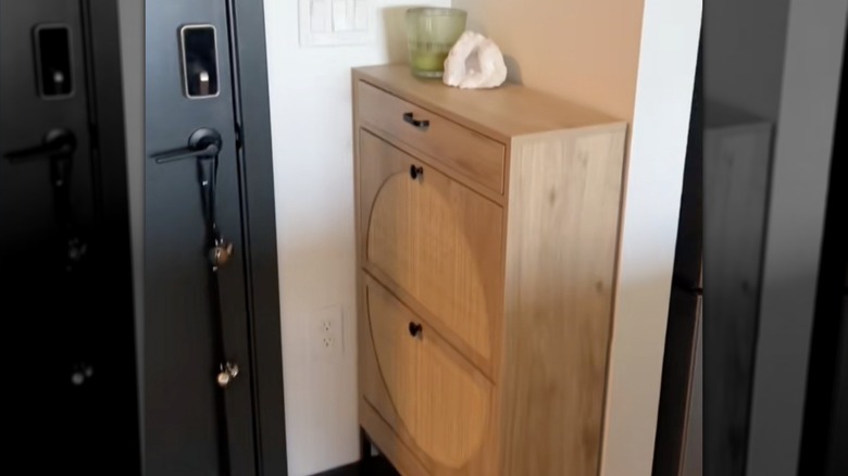 Screenshot of makeshift entryway with a narrow, wooden compact entryway table. Candle and stone on top of the shelf.