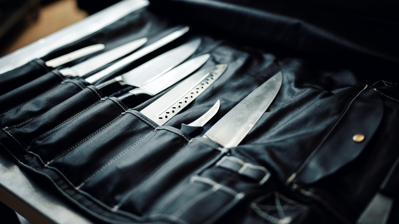A wide variety of steel kitchen knives in a black roll case