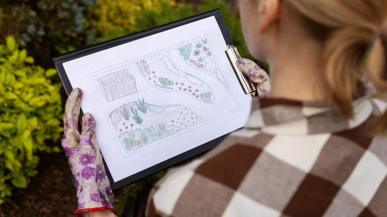 Over the shoulder shot of woman looking at a sketch of a garden design.