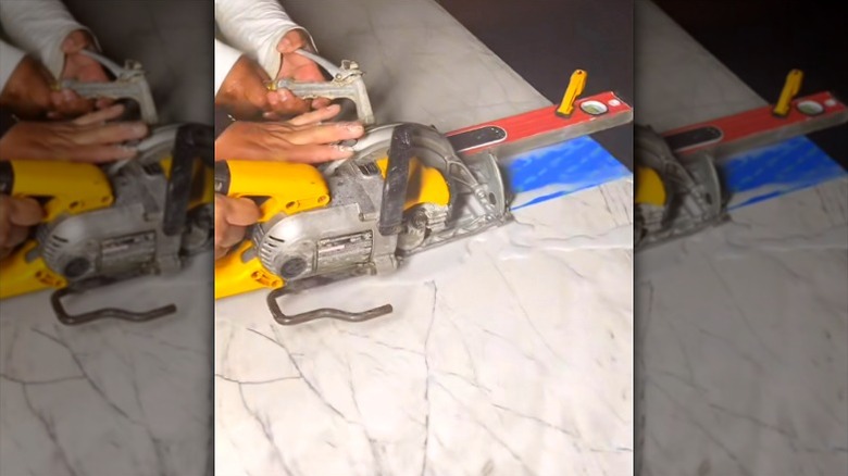 person pushing circular saw across wet quartz countertop