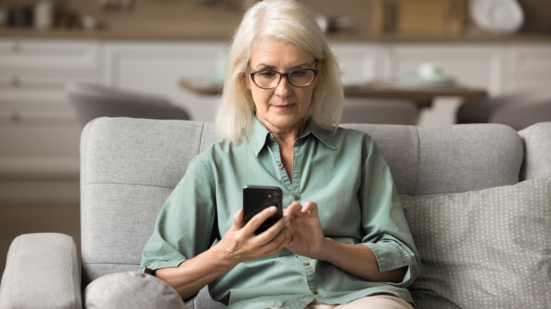 Senior woman in a neat living room setting reminder on her phone