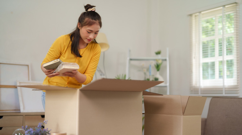young woman taking books out of a box