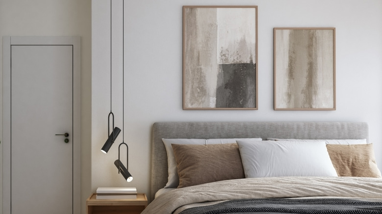 Unique light fixture next to a neutral bed
