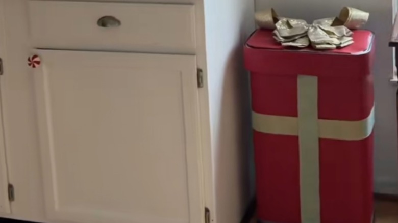 A trash can in holiday wrapping paper and ribbon.