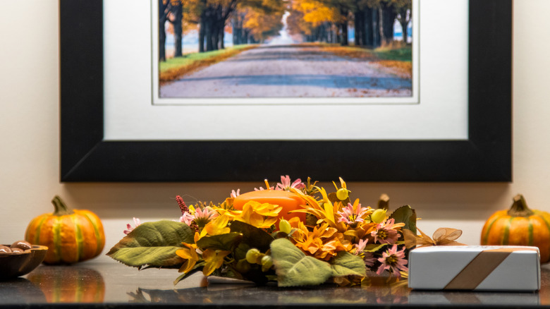 Thanksgiving decorations on sideboard with autumn painting on the wall