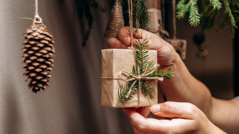 Closeup of person's hands hanging decorations made from pine cones and sprigs