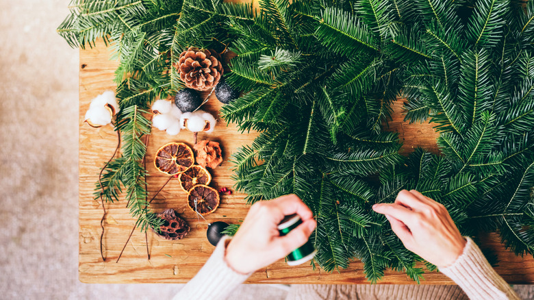 Closeup of person's hands creating a wreath from pine branches