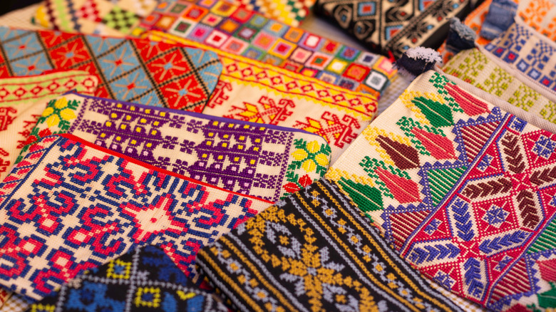 Exquisite hand embroideries in multiple designs and colors, displayed on table in an artistic handicraft workshop that blends authenticity and modernity