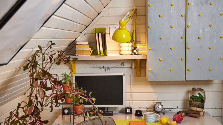Slanted ceiling and walls of a home office area are covered in shiplap