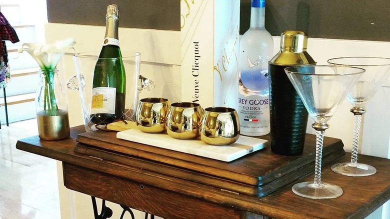 A wooden bar cart with fancy glasses and alcohol.