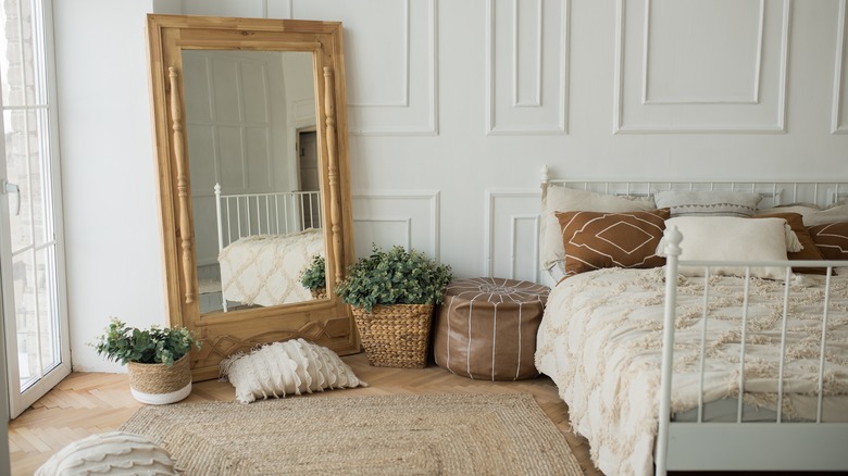 large mirror in corner of white bedroom