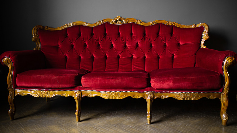 Red velvet couch with gold details.