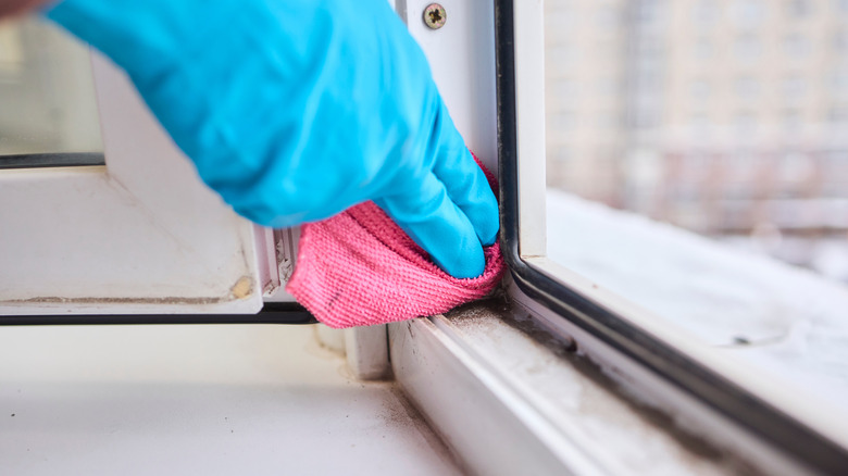 Gloved hand wiping a window track