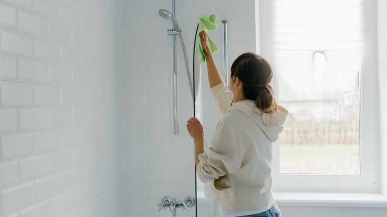 A person cleaning the glass door on shower