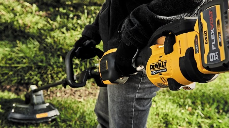 Person using a DeWalt 60V string trimmer on weeds