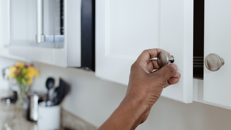 Person opening painted kitchen cabinet door