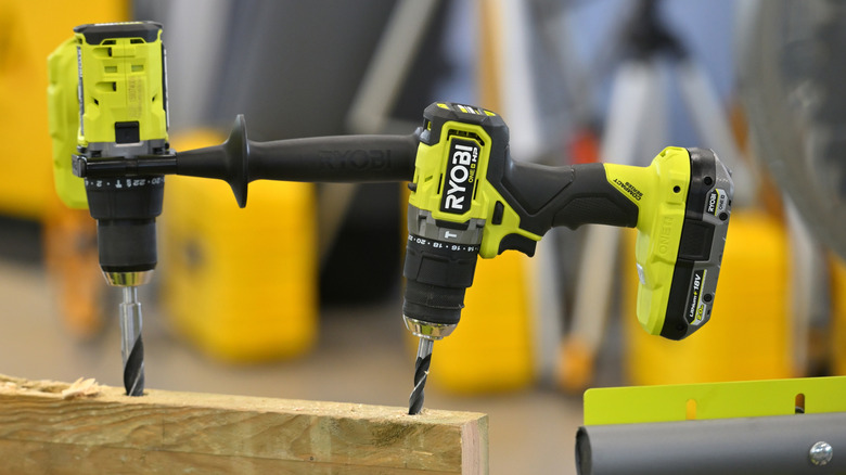 Two Ryobi cordless drills with their bits stalled in a board