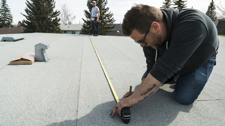 A person measuring the area of a roof