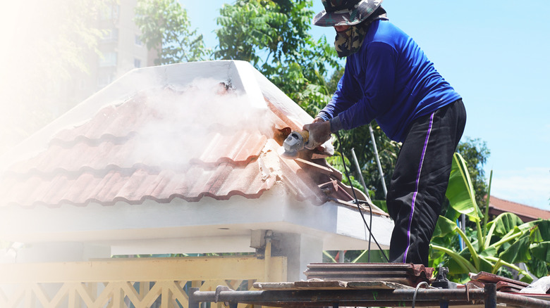 A worker using a grinder for cutting roof shingles