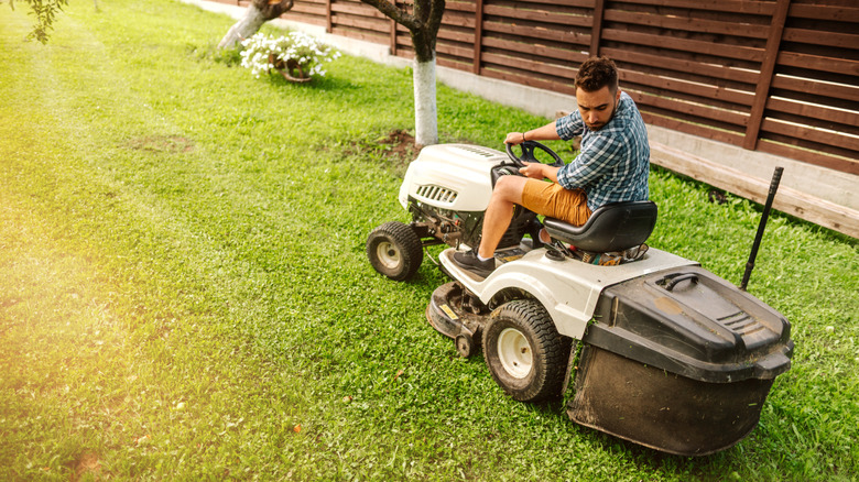 Man using a white riding mower to mow his lawn