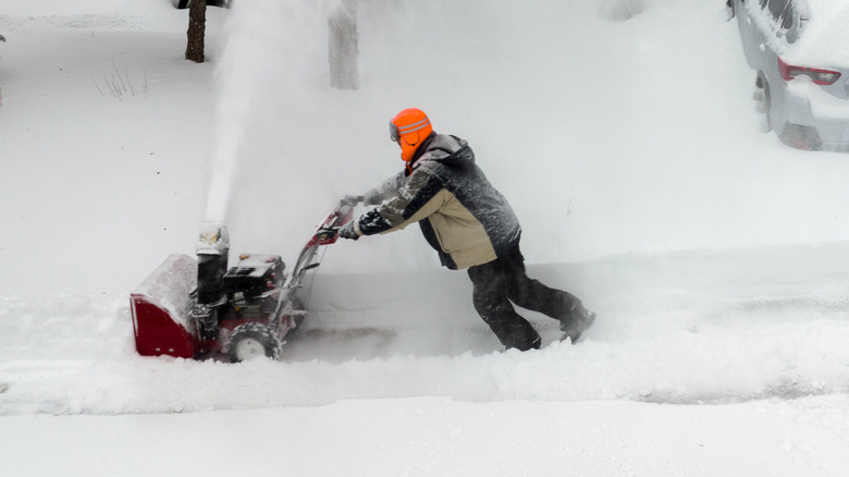 A man using a two-stage snow blower in deep snow