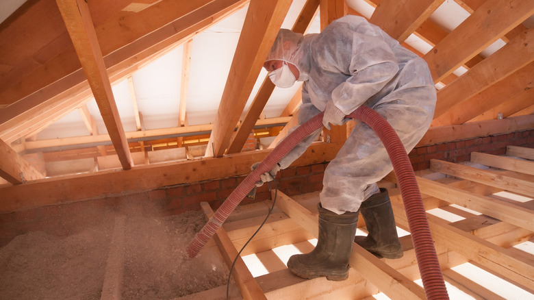 Worker spraying loose fill insulation