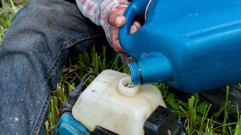 Person pouring gas into trimmer