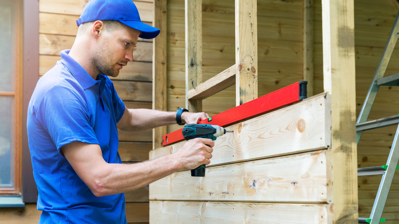 Young guy in the process of building a wooden shed