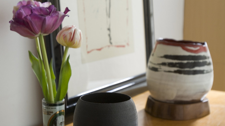 Close up of decor on top of entryway table, including a vase, ceramic decor, and a painting.