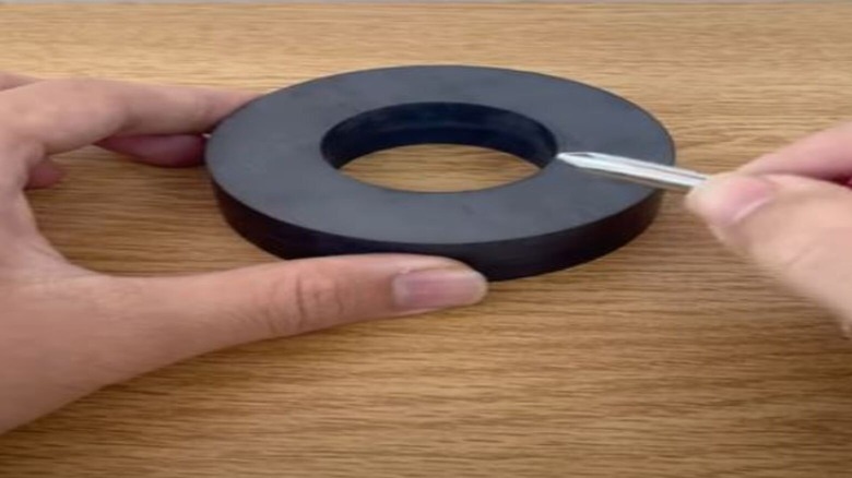 Man rubbing screwdriver to a magnet