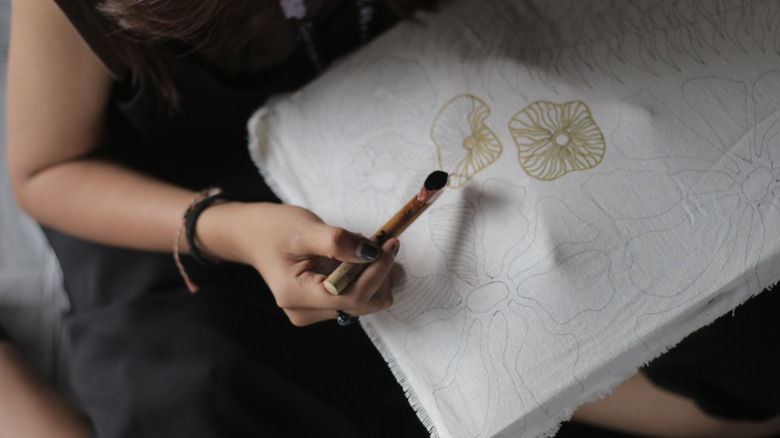 A person's hand painting fabric