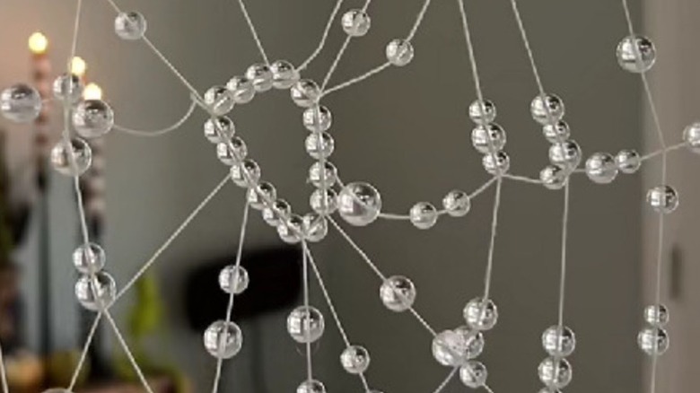 A fake spider web Halloween decoration made using string and beads