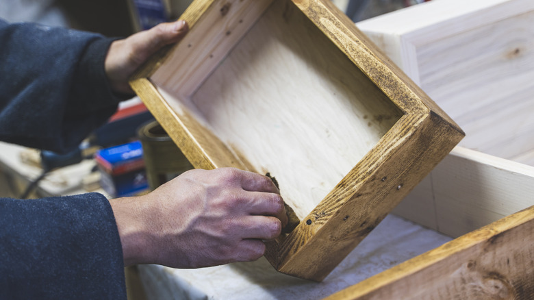 A man applying finish to a wooden box