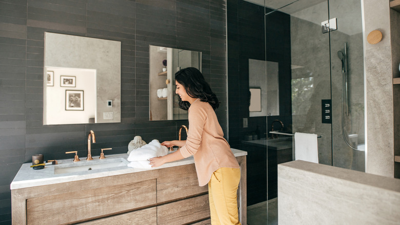 A woman tidies her bathroom vanity.