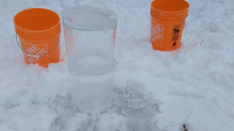 Two ice lantern pieces stacked outside next to orange buckets