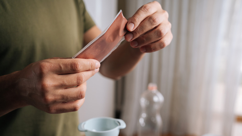 A person holds a packet of hydroponics mix above a funnel.