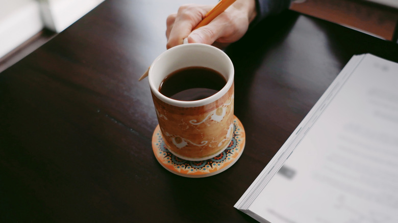 Person drinking coffee at desk using a coaster