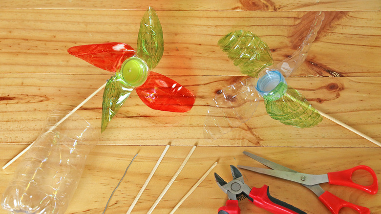 Pinwheels made from plastic bottles and craft tools on a wooden tabletop.