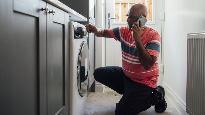 Man on the phone fixing broken washing machine