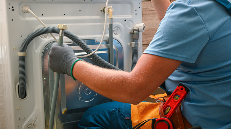 Repair person fixing a laundy machine drain hose