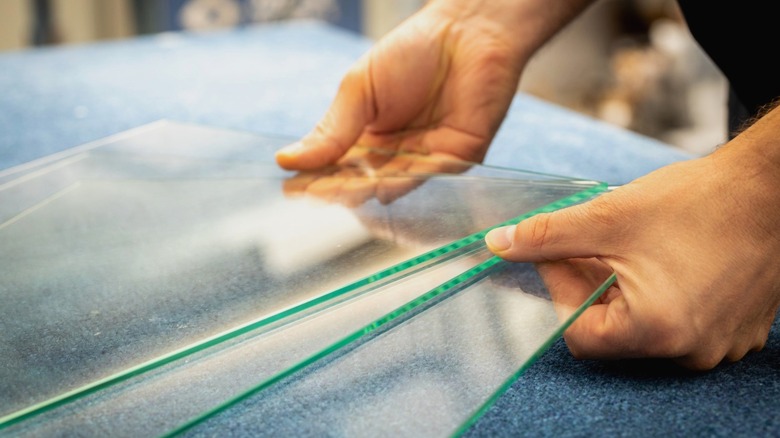 Person holding three thin glass panes in shop