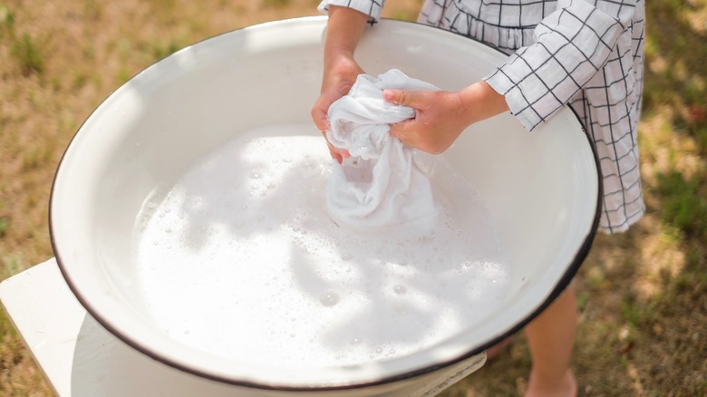 Hand washing clothes in bucket