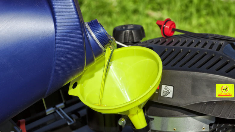 pouring oil to lawn mower